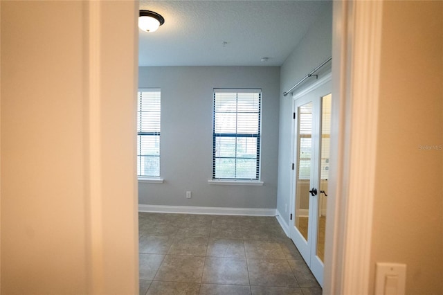 doorway with dark tile patterned floors, baseboards, and french doors