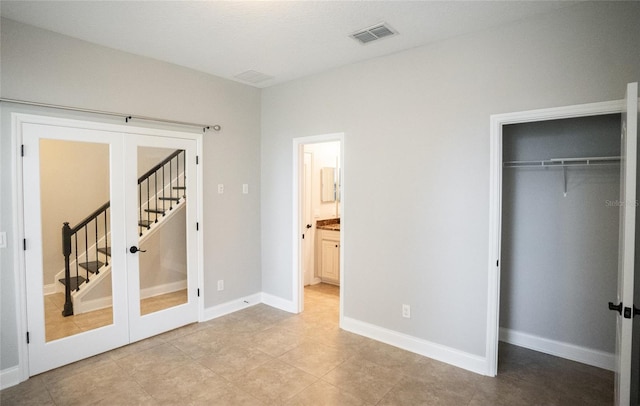 unfurnished bedroom featuring baseboards, visible vents, ensuite bathroom, french doors, and light tile patterned flooring