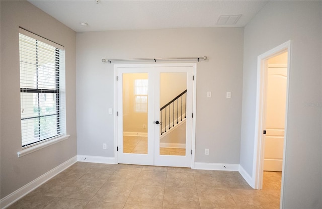 interior space with light tile patterned floors, french doors, and baseboards