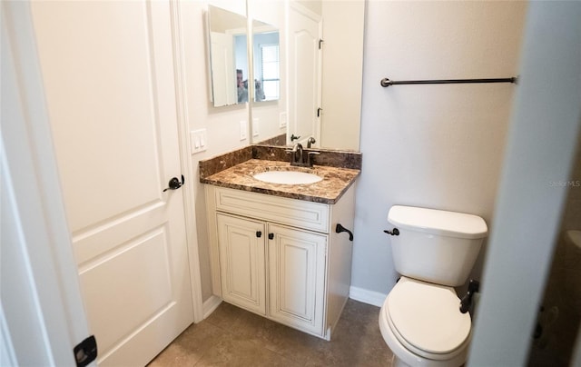 bathroom featuring toilet, vanity, and baseboards