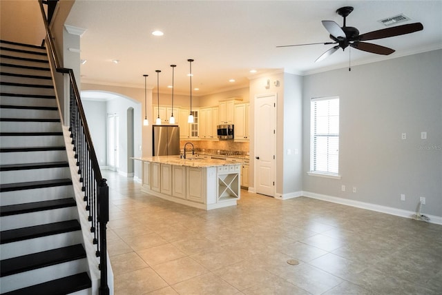 kitchen featuring a kitchen island with sink, a sink, appliances with stainless steel finishes, glass insert cabinets, and pendant lighting