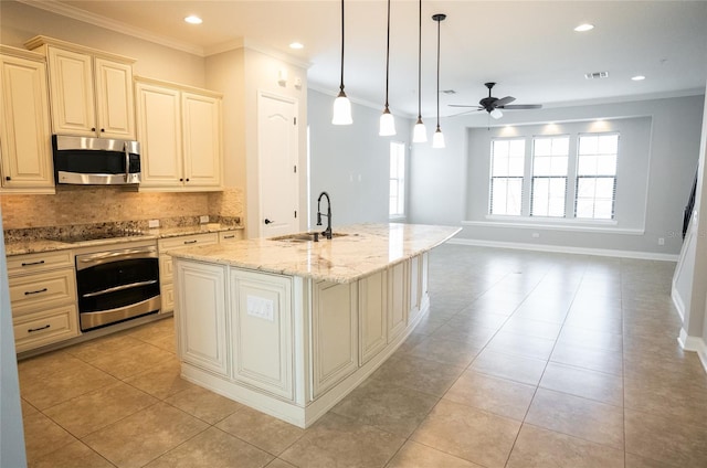 kitchen featuring light stone counters, hanging light fixtures, a kitchen island with sink, stainless steel appliances, and a sink