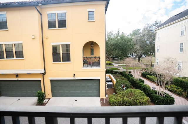 multi unit property featuring central AC, concrete driveway, an attached garage, and stucco siding