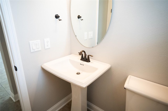 bathroom with baseboards, a sink, and toilet