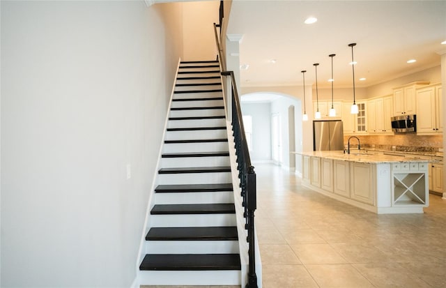 stairway featuring arched walkways, recessed lighting, baseboards, ornamental molding, and tile patterned floors