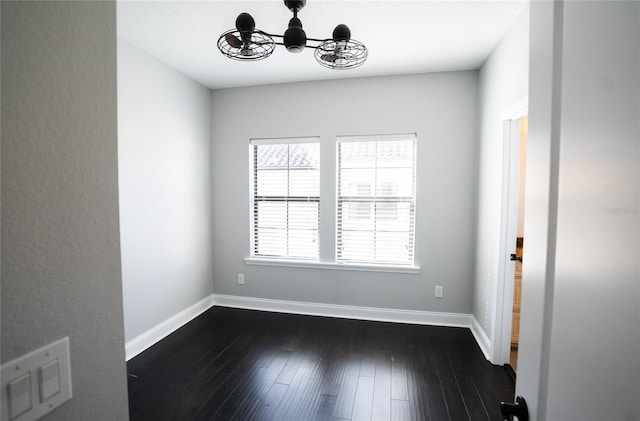 spare room featuring dark wood-style flooring and baseboards