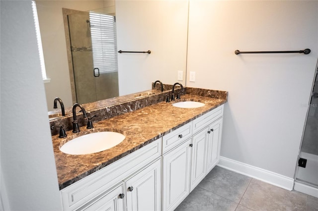 full bathroom featuring a stall shower, a sink, baseboards, and double vanity