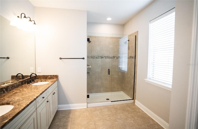 bathroom featuring tile patterned flooring, a sink, a shower stall, and baseboards