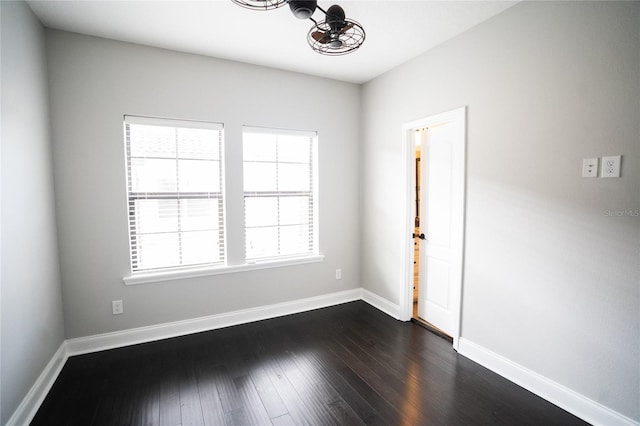 spare room with baseboards and dark wood-type flooring