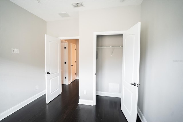 unfurnished bedroom featuring dark wood finished floors, visible vents, and baseboards