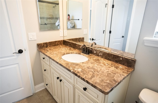 bathroom featuring toilet, tile patterned flooring, baseboards, and vanity