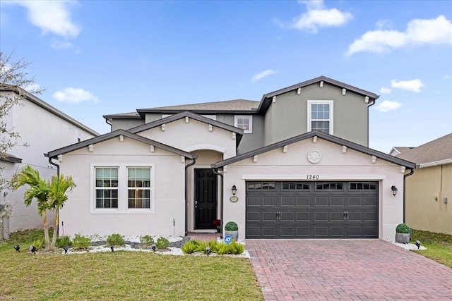 traditional home featuring a garage, decorative driveway, a front lawn, and stucco siding