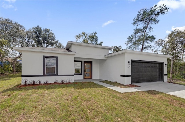 view of front facade featuring an attached garage, driveway, a front yard, and stucco siding