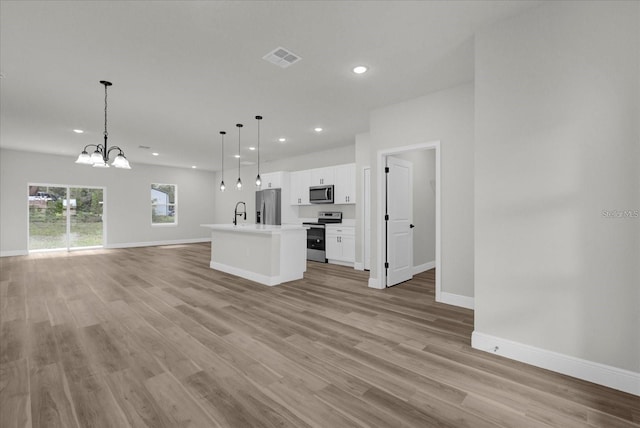 kitchen with stainless steel appliances, open floor plan, visible vents, and light wood-style floors