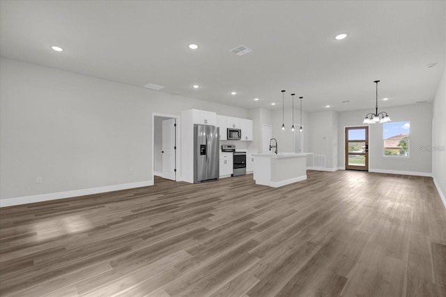 unfurnished living room with baseboards, visible vents, light wood-style flooring, a sink, and recessed lighting