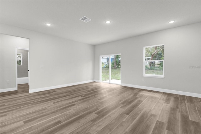 empty room with baseboards, visible vents, wood finished floors, and recessed lighting