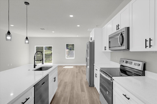 kitchen with stainless steel appliances, a sink, light countertops, and pendant lighting