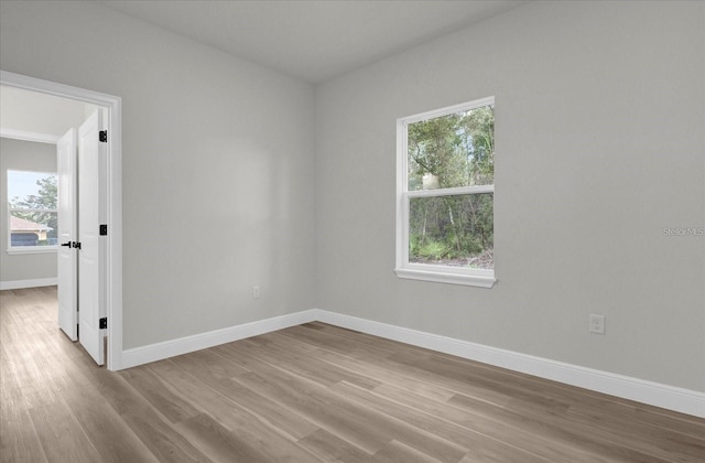 spare room featuring baseboards and wood finished floors