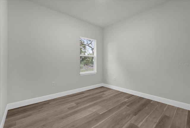 spare room with dark wood-type flooring and baseboards