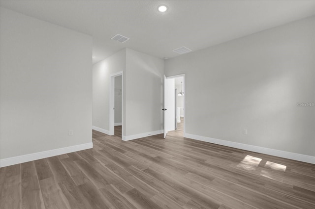 empty room featuring visible vents, baseboards, and wood finished floors