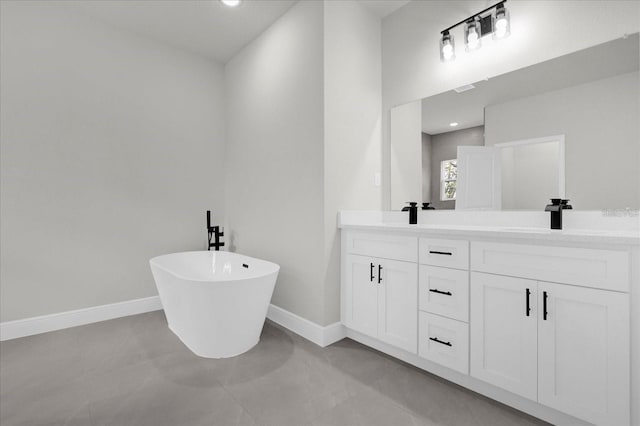 bathroom with double vanity, a soaking tub, a sink, and baseboards