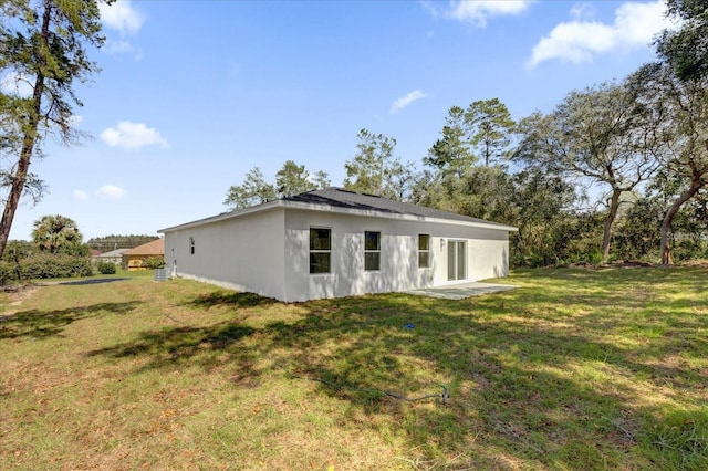 rear view of house featuring a yard and stucco siding