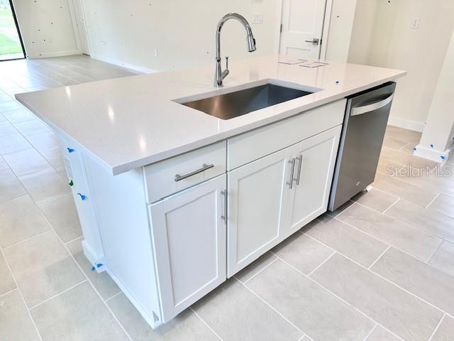 3219 Cup Dr, Lakeland, FL 33803 - kitchen featuring a sink, stainless steel dishwasher, light tile patterned floors, white cabinetry, and light countertops