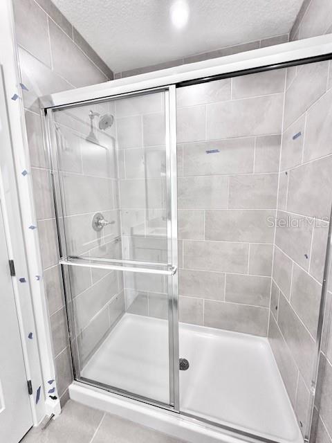 3219 Cup Dr, Lakeland, FL 33803 - bathroom with a textured ceiling, a shower stall, and tile patterned flooring
