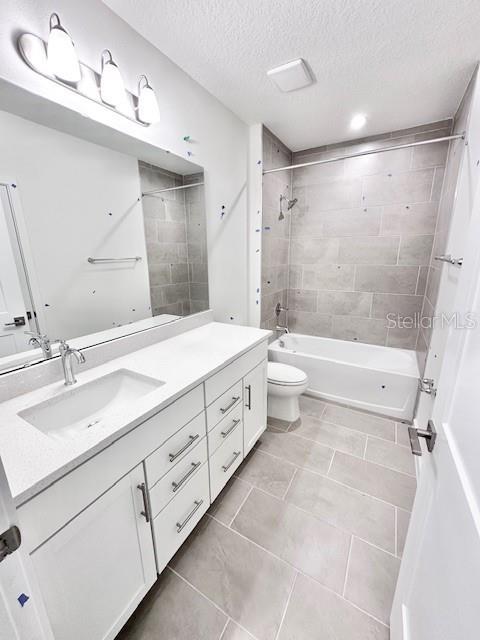 3219 Cup Dr, Lakeland, FL 33803 - bathroom featuring tile patterned flooring, toilet, vanity, a textured ceiling, and shower / bathtub combination