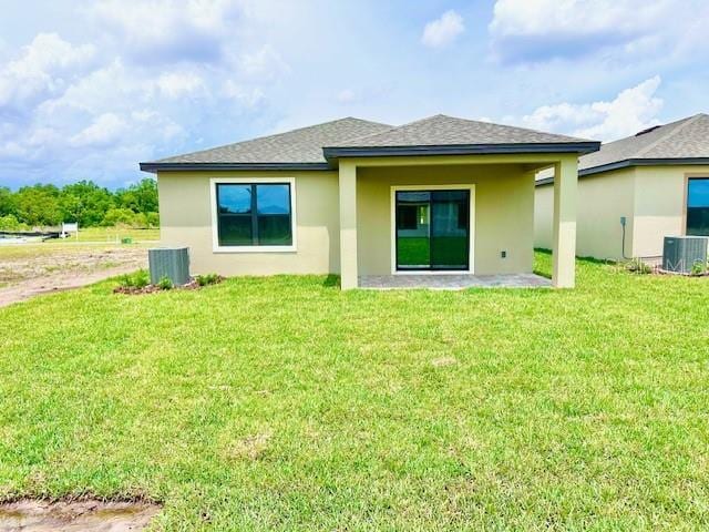 3219 Cup Dr, Lakeland, FL 33803 - rear view of house with stucco siding, a yard, cooling unit, and roof with shingles