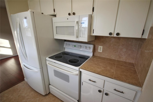 6026 22nd Ave N Unit 4, Saint Petersburg, FL 33710 - kitchen featuring white appliances, light tile patterned floors, white cabinets, and tasteful backsplash