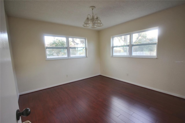 6026 22nd Ave N Unit 4, Saint Petersburg, FL 33710 - spare room featuring a textured ceiling, dark wood-type flooring, a chandelier, and a wealth of natural light