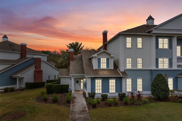 view of front of house featuring a shingled roof, a chimney, and a front yard