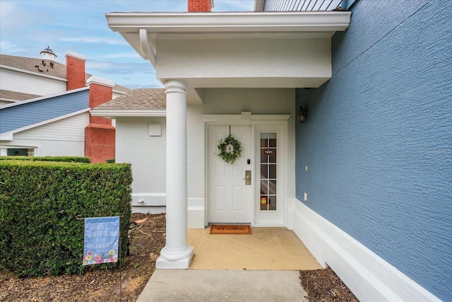 property entrance featuring roof with shingles and stucco siding