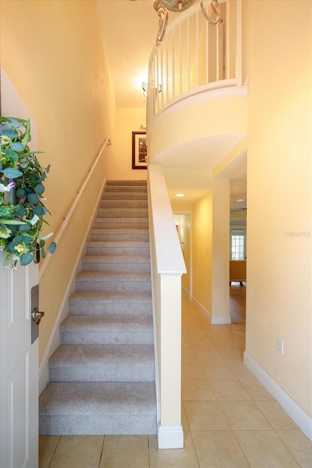 stairway featuring a high ceiling, baseboards, and tile patterned floors