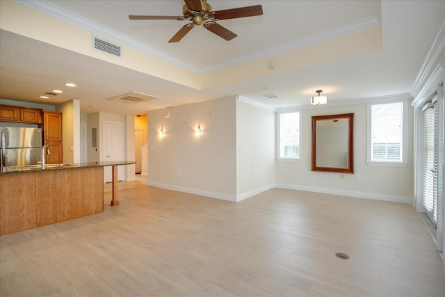 empty room with light wood-type flooring, a healthy amount of sunlight, crown molding, and baseboards