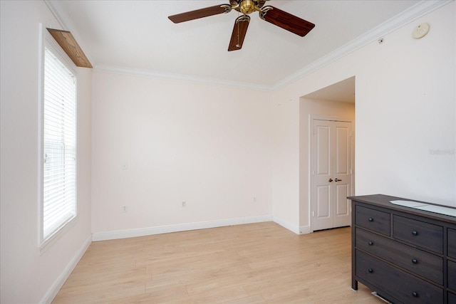 spare room featuring baseboards, plenty of natural light, light wood-style flooring, and crown molding