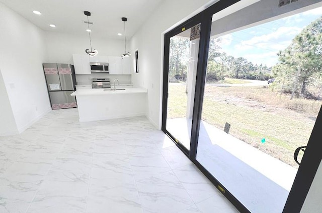 kitchen featuring decorative light fixtures, stainless steel appliances, white cabinets, and a healthy amount of sunlight