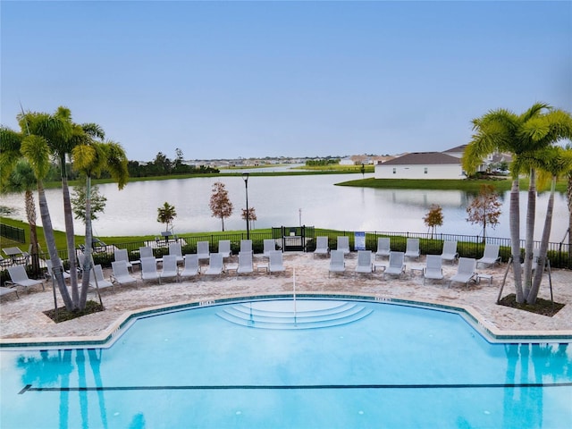 pool featuring a water view, fence, and a patio