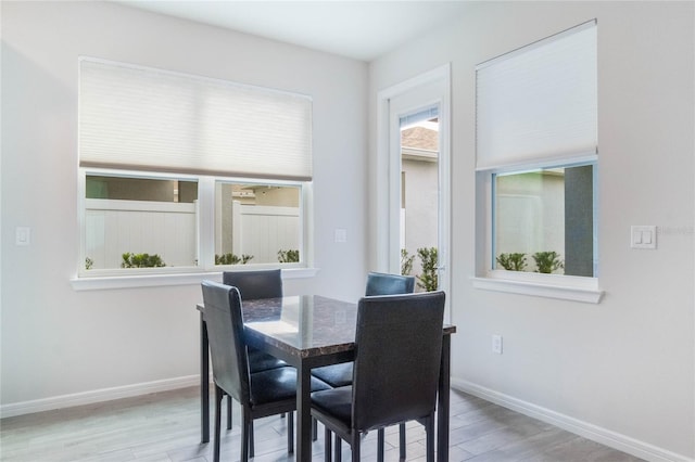 dining space with light wood-type flooring and baseboards