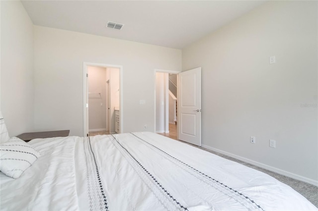 bedroom featuring baseboards, connected bathroom, visible vents, and carpet flooring