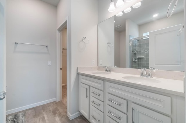 bathroom with a spacious closet, double vanity, a sink, and a shower stall