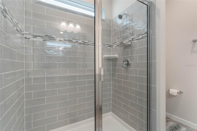 bathroom with a shower stall and baseboards