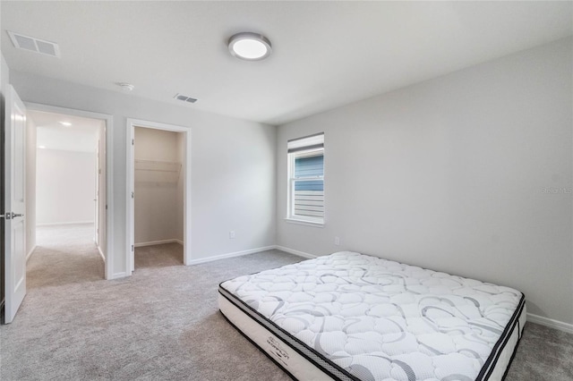 bedroom with carpet flooring, visible vents, and a walk in closet