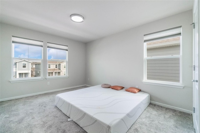 bedroom featuring light colored carpet and baseboards