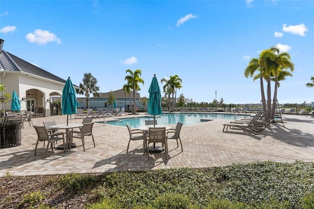 community pool with a patio and fence