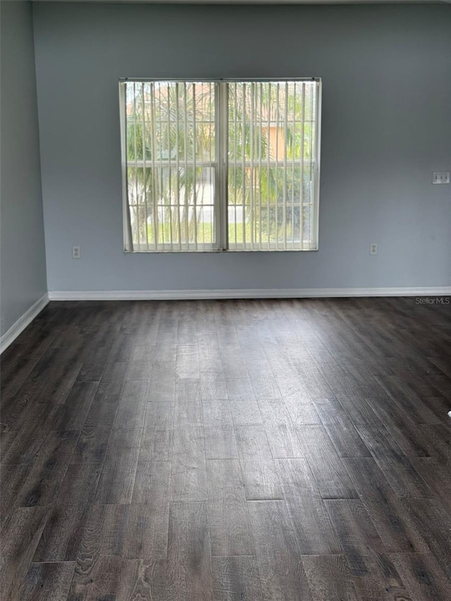 empty room with dark wood-style floors and baseboards