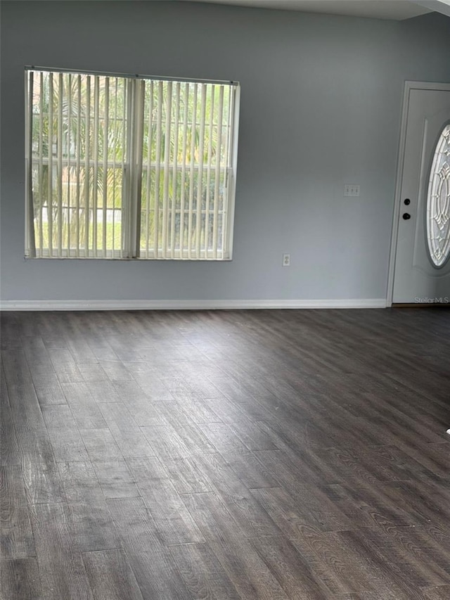 unfurnished room featuring dark wood-type flooring and baseboards