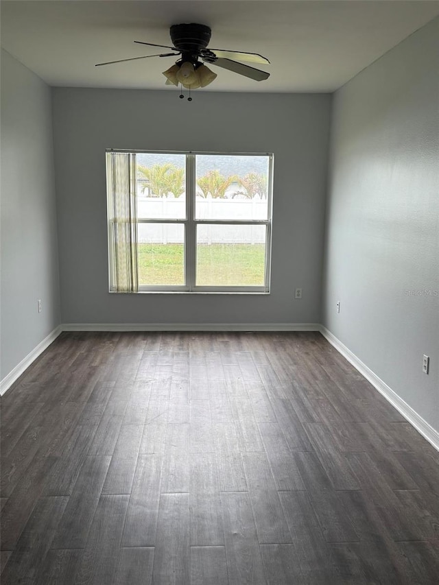 empty room featuring ceiling fan, baseboards, and dark wood finished floors