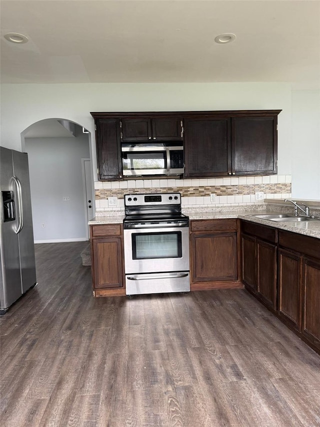 kitchen with backsplash, dark wood finished floors, stainless steel appliances, and a sink